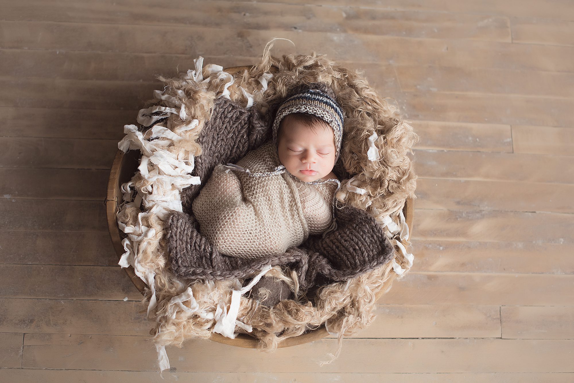 newborn baby boy swaddled in nest on the floor