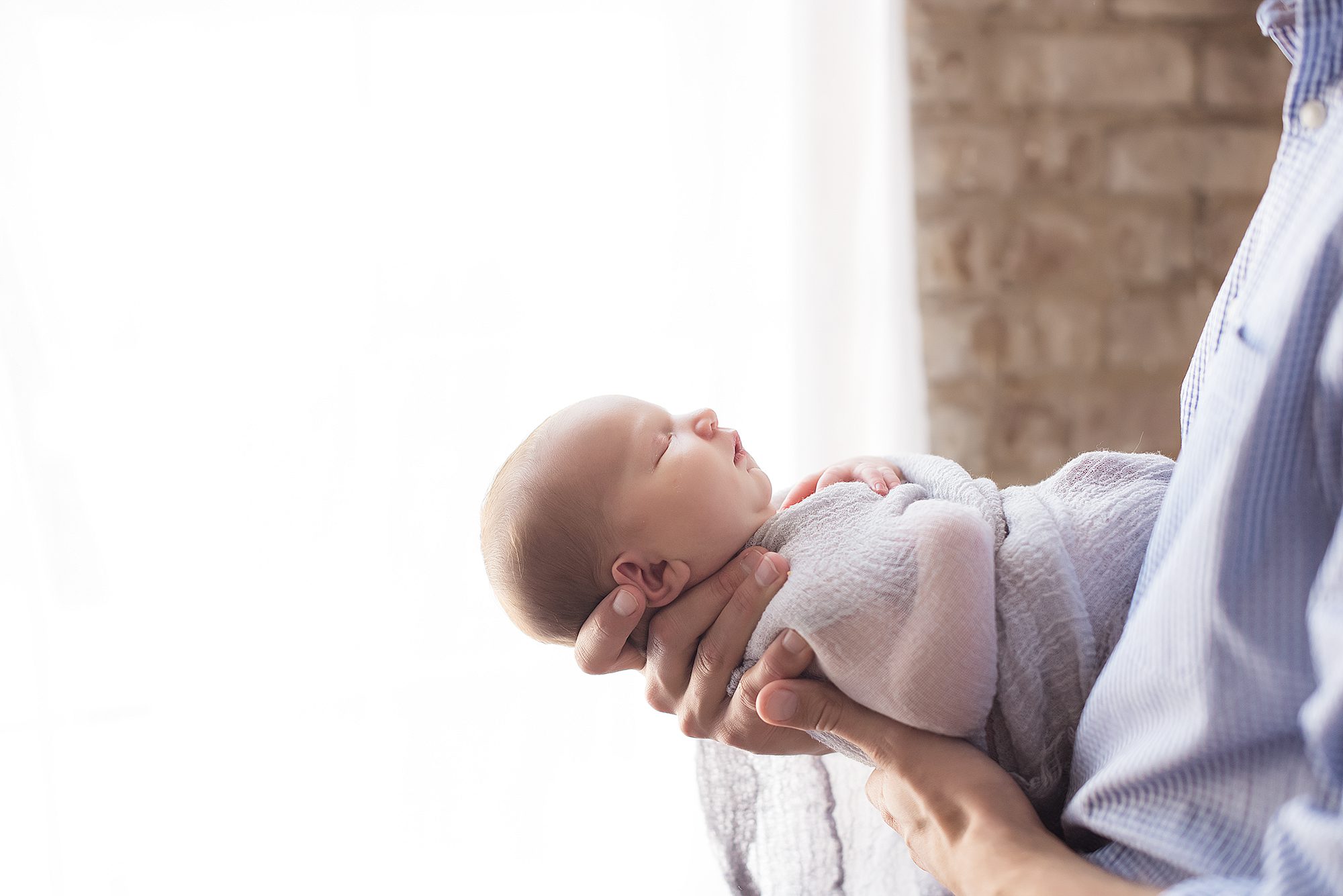 dad holding newborn baby girl wrapped in blue blanket