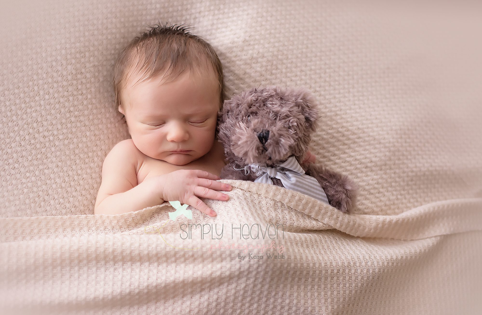 Newborn baby boy snuggling with his lovie teddy bear. 