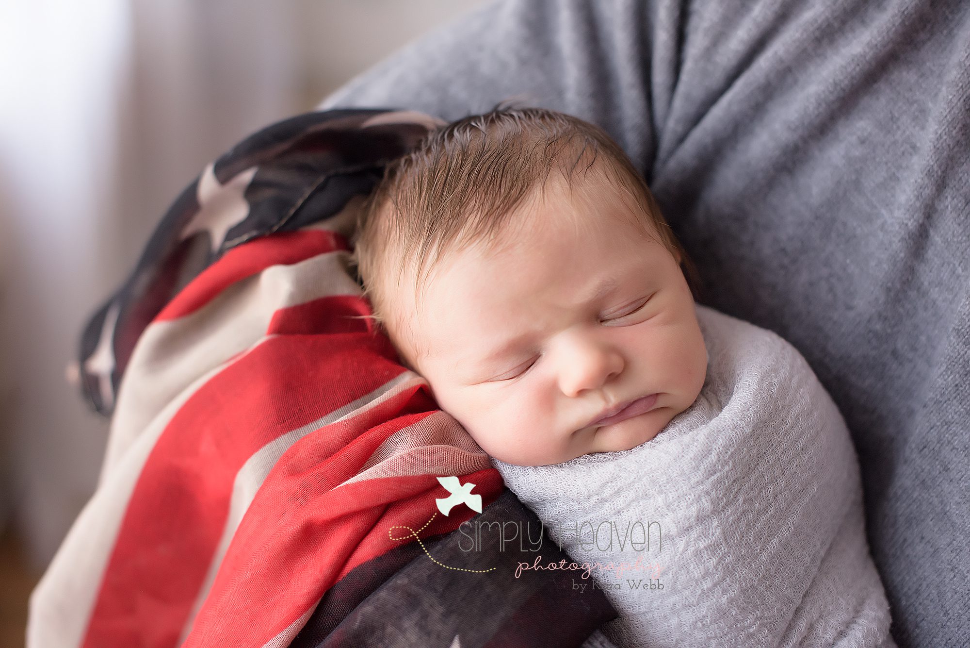 dad holding newborn baby boy while wrapped in a flag
