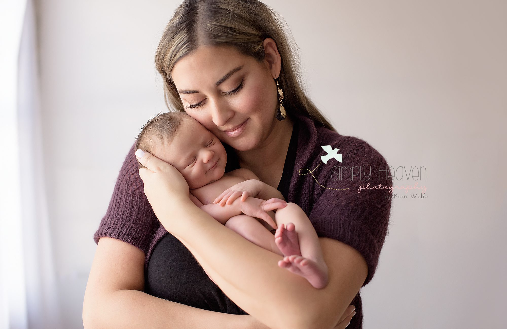 mom snuggling newborn baby boy's cheek while he smiles