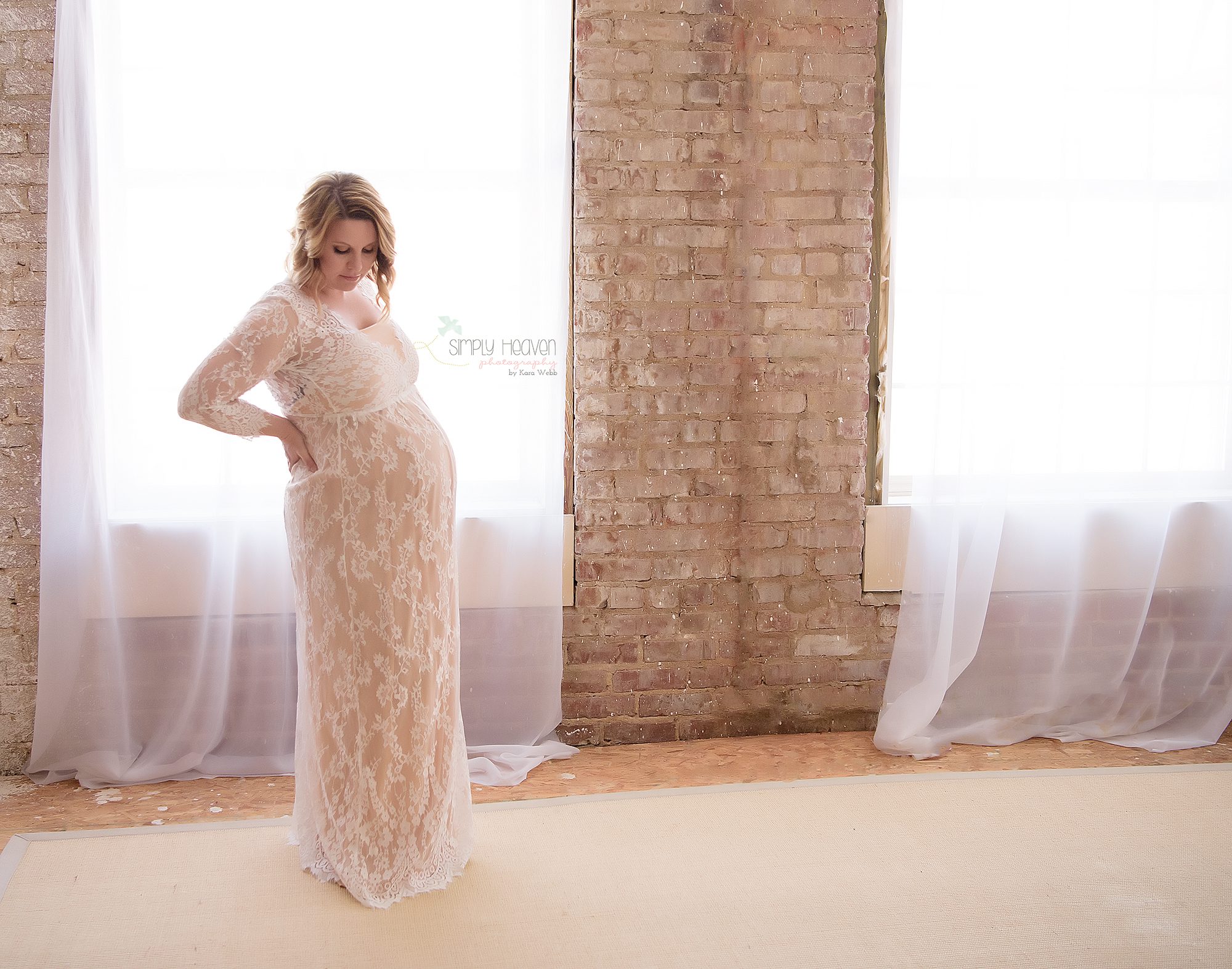 matenity portrait of mom standing in front of a window in a white dress