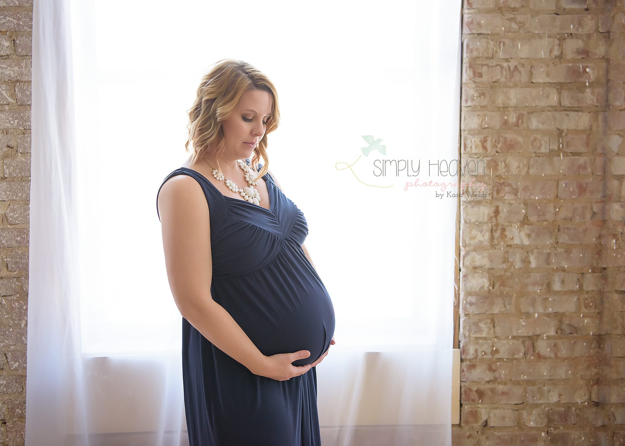 pregnant woman in a navy blue dress in front of a window