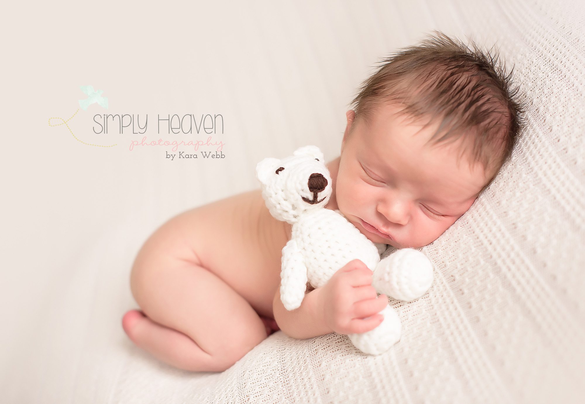 newborn baby boy snuggling a teddy bear