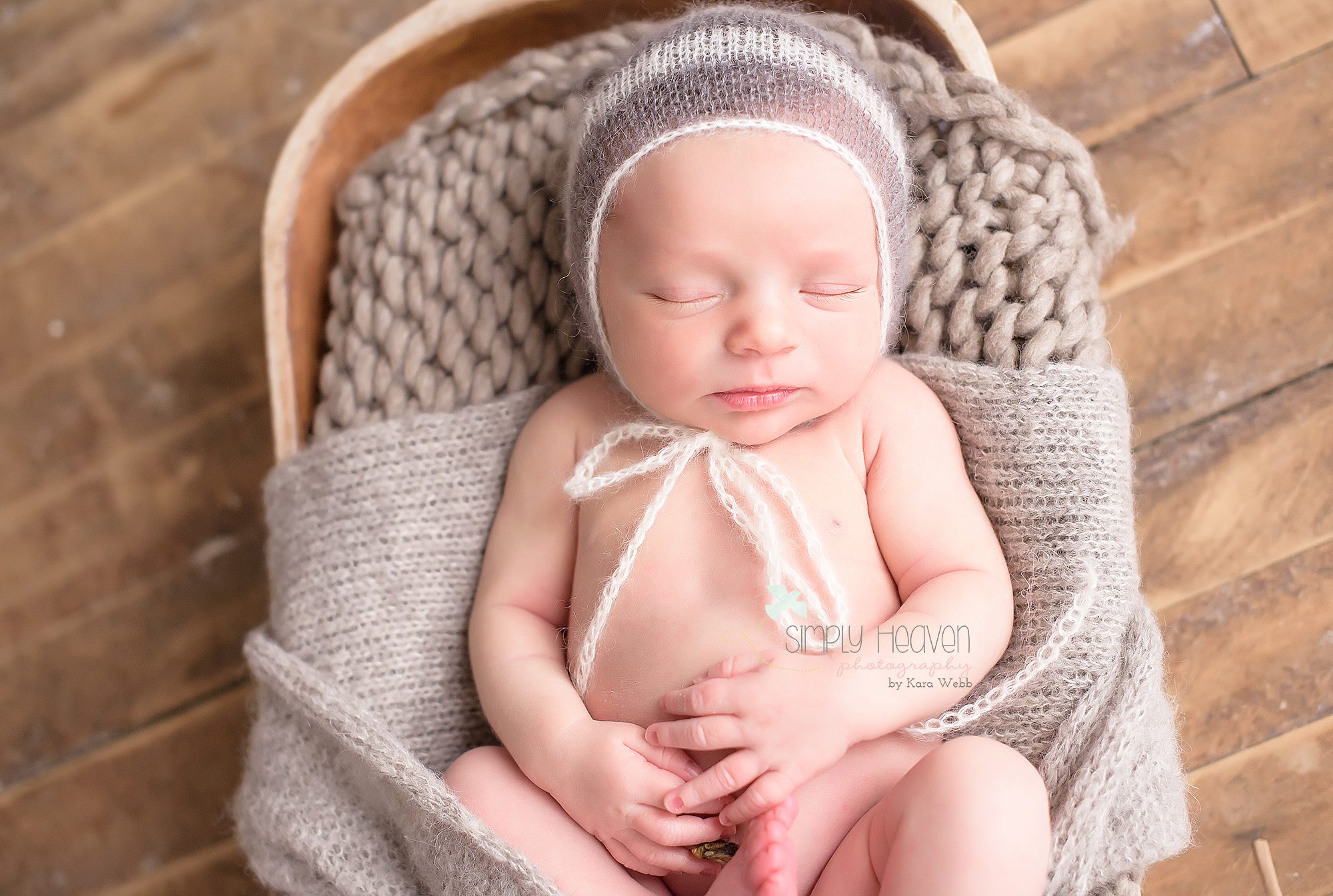 newborn baby boy wrapped in a cream net with gray hat