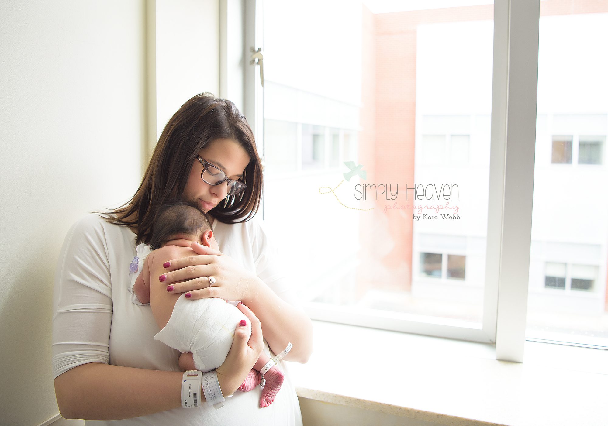 fresh48 picture of a mom holding her newborn baby girl in her arms in front of a hospital window