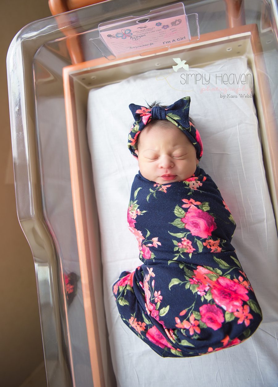 newborn baby girl in a crib bassinet