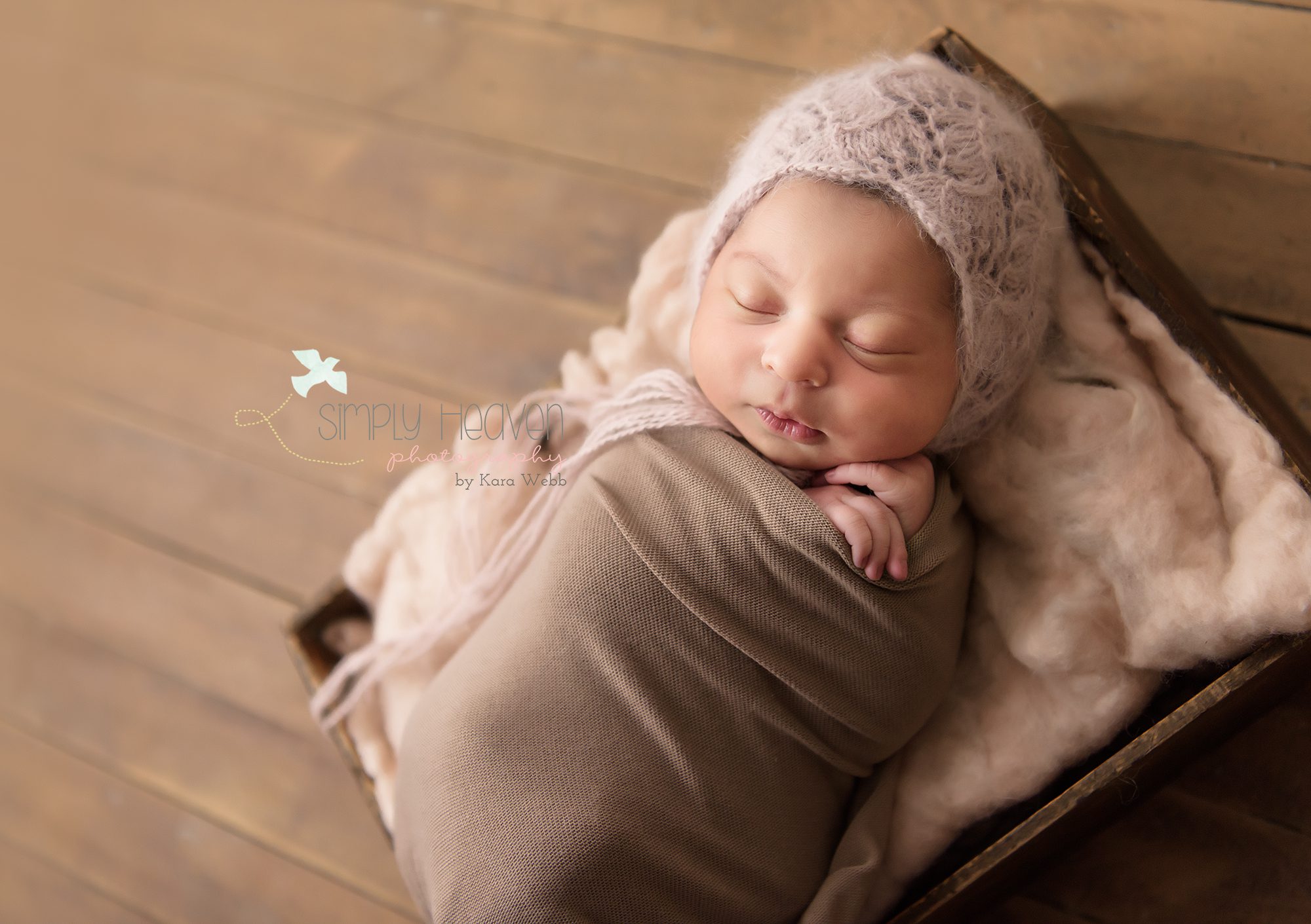 newborn baby girl swaddled in a fawn color with a soft pink angora bonnet