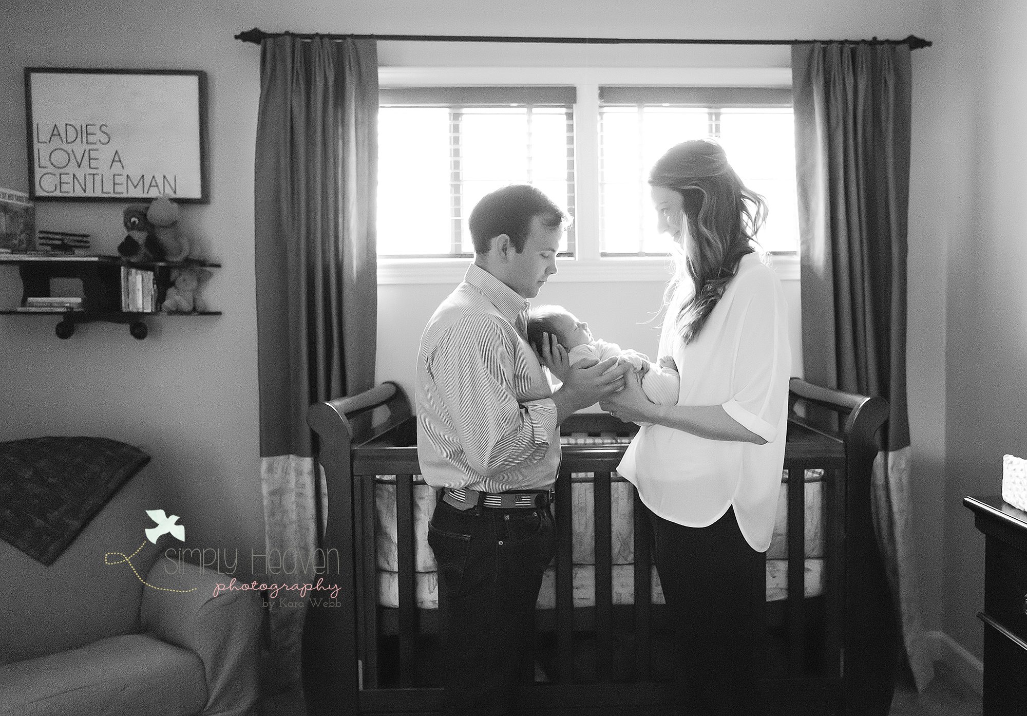 mom and dad holding newborn baby boy in his nursery