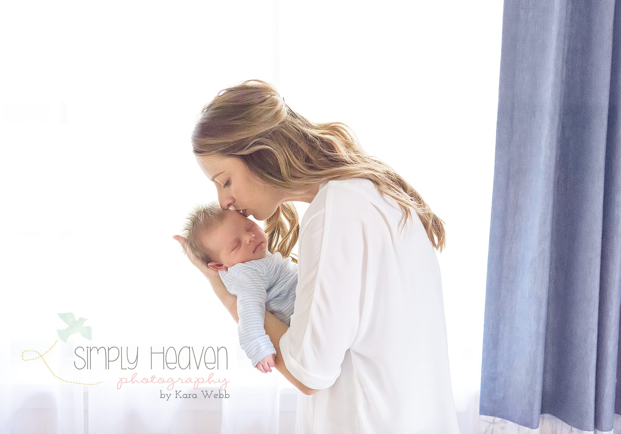 mom holding her newborn baby boy in front of a window