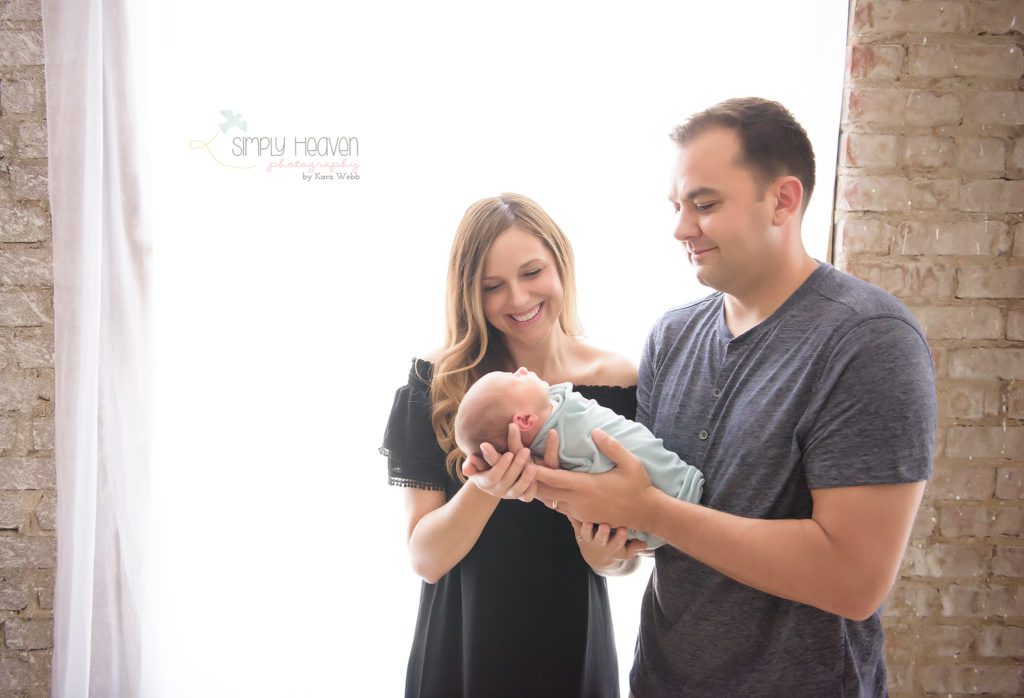 mom and dad holding a swaddled baby boy