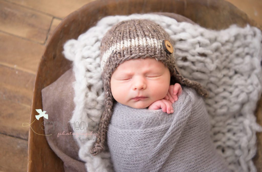 newborn baby boy wrapped in a brown and gray swaddle 