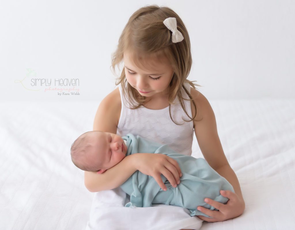 big sister looking at newborn baby brother
