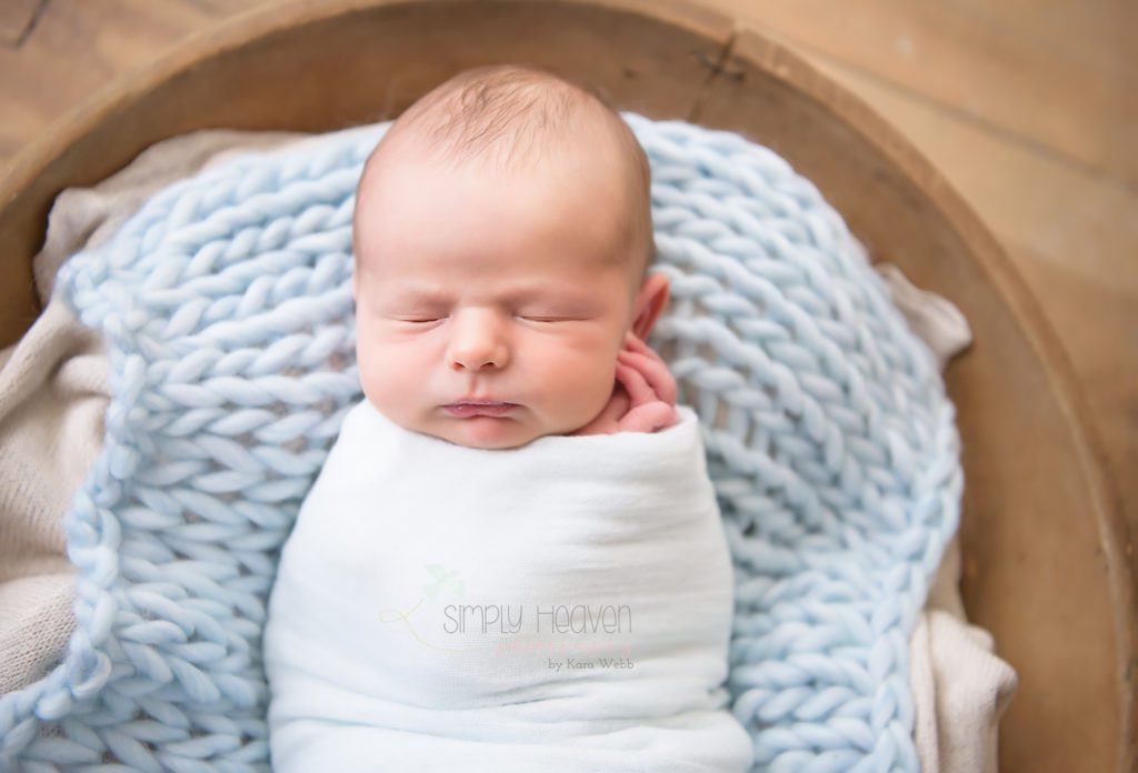 newborn baby boy wrapped in a blue swaddle 