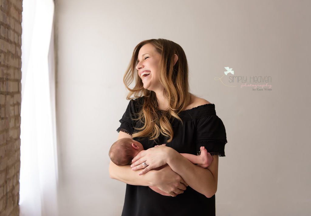 laughing mom holding a newborn baby boy