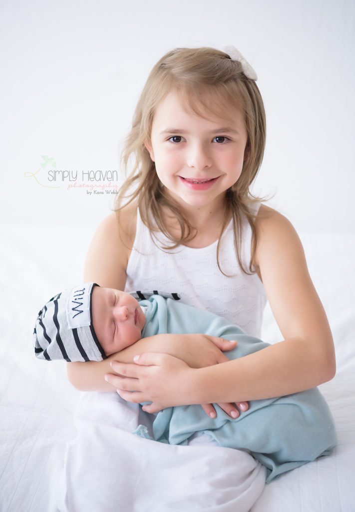 big sister holding newborn baby brother