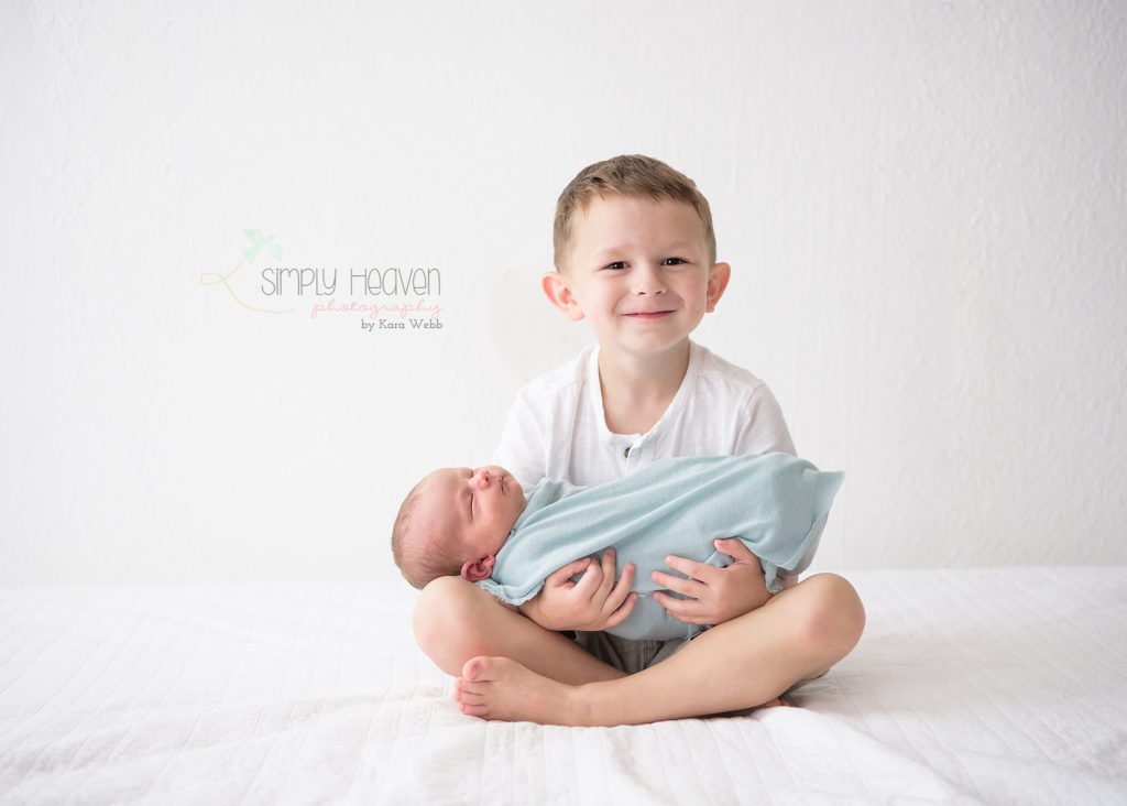 big brother holding newborn baby brother